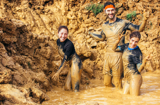 Participants in extreme obstacle race, running through mud