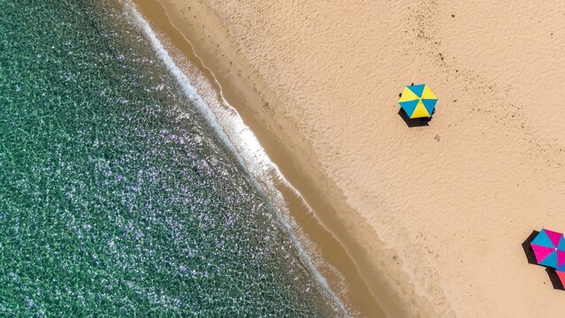 A drone captures an aerial view of a sandy beach with an umbrella
