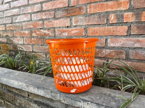 Trash can and red brick wall with plants underneath