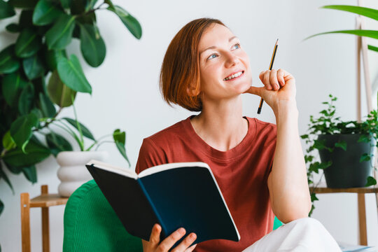 Thoughtful woman holds an open notebook in her home office