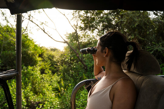 Woman on jungle safari observing nature with binoculars in Sri Lanka
