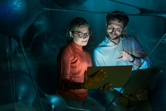 Man and woman analyze data on a laptop in a dark organic network