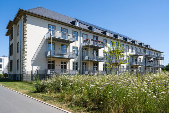 Renovated barrack building stands behind a flower meadow in Soest