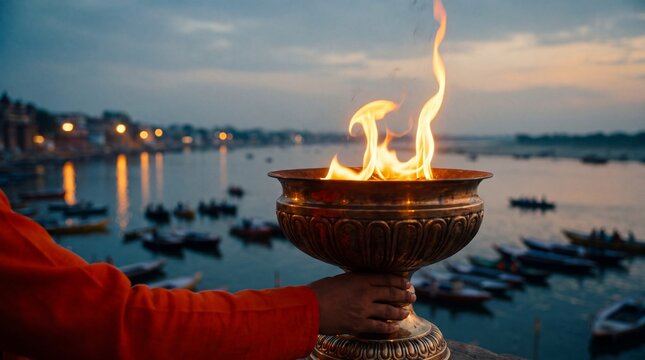 Vibrant flames engulf traditional Indian lamp at serene river ghats during sunset