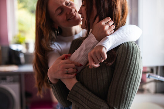 Lesbian couple cuddling affectionately at home in the morning
