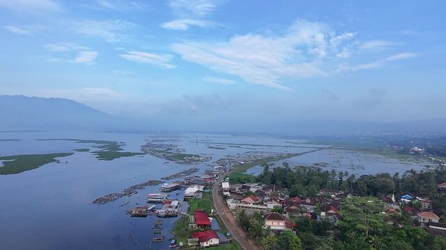 Beautiful aerial drone view of the Blue Bridge (Jembatan Biru Sumurup) at Rawa Pening lake with local village houses in Semarang, Central Java, Indonesia.
