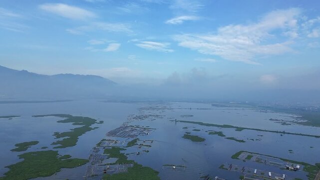 Beautiful aerial drone view of the Blue Bridge (Jembatan Biru Sumurup) at Rawa Pening lake with local village houses in Semarang, Central Java, Indonesia.