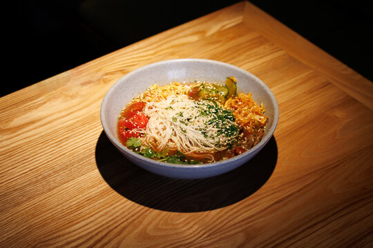 Warm bowl of noodles sits on wooden table