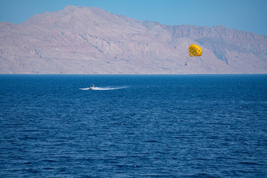 Yellow parasail over blue sea with mountain coastline