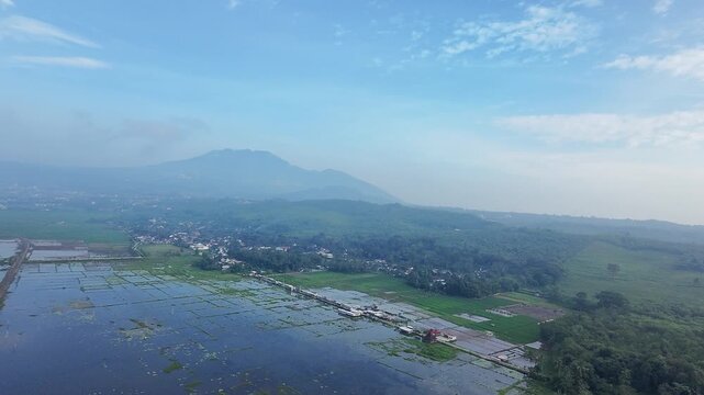 Beautiful aerial drone view of the Blue Bridge (Jembatan Biru Sumurup) at Rawa Pening lake with local village houses in Semarang, Central Java, Indonesia.