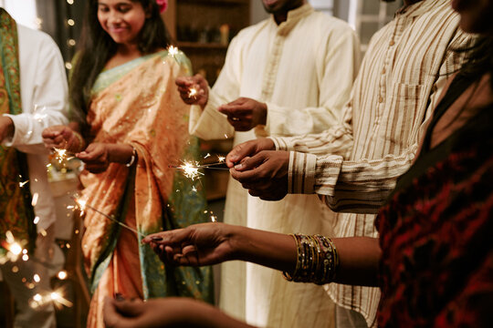 Diverse group of young adult Indian friends celebrating cultural festival holding sparklers together. Image useful for holiday marketing campaigns and social diversity media