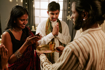 Obraz premium Indian young adults and teenager praying during religious ritual at home celebrating festival of lights. Concept of cultural tradition suitable for holiday advertising campaigns