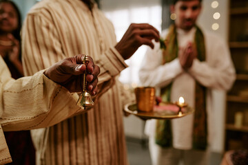 Obraz premium Indian family celebrating festival with prayer ritual holding brass bell and oil lamp tray. Suitable for cultural event marketing, holiday advertising, and religious celebration content