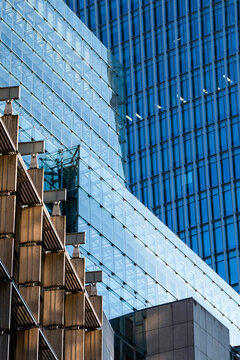 Modern glass buildings overlap in a city view where urban facades and reflections create geometry and contrast across the architecture