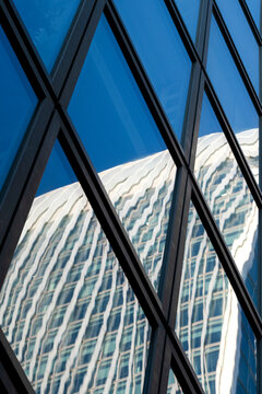Reflection across a modern glass facade turns architecture into an abstract pattern as windows and geometry reshape the building visually