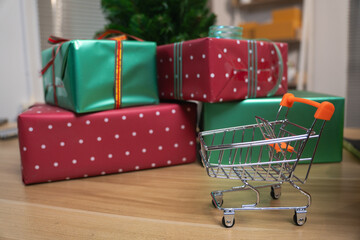 Miniature shopping cart next to stacked Christmas gift boxes for holiday sale concept © Oil And Den