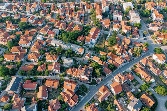 Densely packed residential streets lined with orange terracotta rooftops, shot from drone altitude. Real estate concept - Balkans.