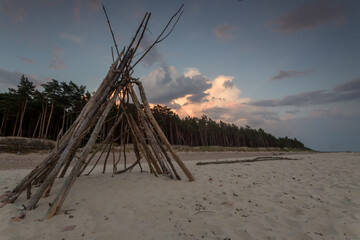 Driftwood Teepee on Quiet Beach at Sunset © Ruslan Bolgov