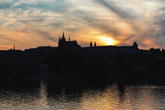 Prague Castle and Saint Vitus Cathedral silhouette at golden sunset over the Vltava river, Czech Republic