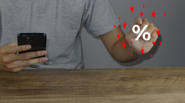Show percentage icon with down red arrows as man holds smartphone, representing special offer shopping department store discount, tax, adjusting interest rate, inflation, and returns on finance