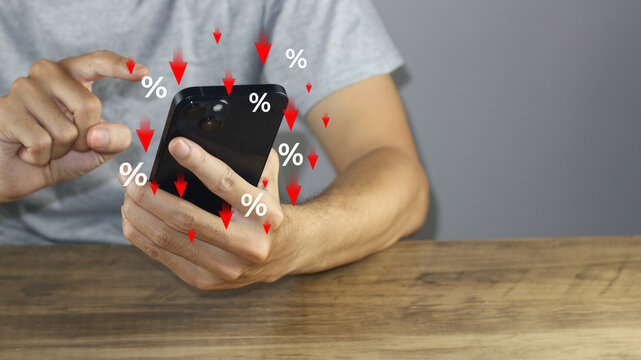Show percentage and red down arrow icons as a man holds a smartphone, representing interest rate cuts, price discounts, tax reduction, inflation adjustments, and finance offer