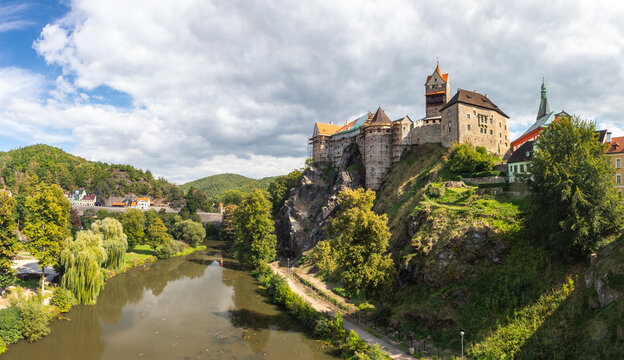 Historic medieval Loket Castle standing on a rocky hill above the Ohre river in Loket town under cloudy sky, Czech Republic