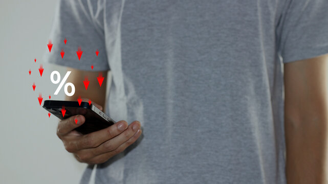 Show percentage symbol with falling red arrows on smartphone screen, symbolizing interest rate cuts, price discounts, tax reduction, and financial investment concepts