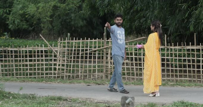 Asian woman in a yellow dress asking a male stranger for directions on a rural village road. Concept of communication, lost traveler, and community interaction
