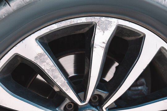 Auto repair and maintenance: dirty alloy wheel with salt corrosion, worn finish, scratches and impact marks from hitting an obstacle.
