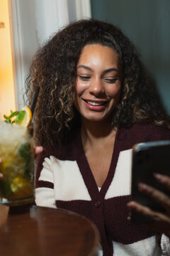 Young woman enjoying drink and smartphone in Madrid bar