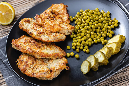 Pork chops fried in batter on a plate with peas