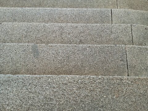 Top-down view of grey stone concrete stairs, highlighting the rough granular texture and parallel horizontal edges