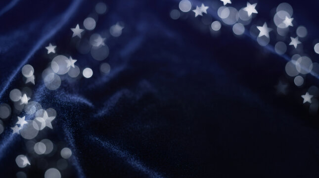 Abstract dark blue velvet background with glowing silver star bokeh and glittering lights