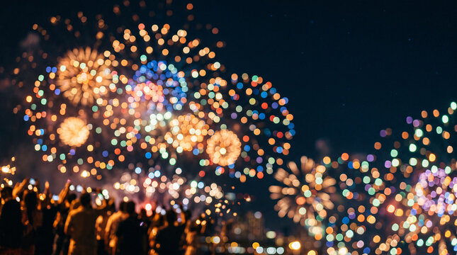 Crowd of silhouetted people watching a spectacular colorful fireworks display in the night sky