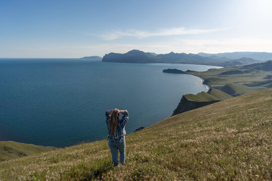 Travel adventure landscape, woman standing on mountain hill top enjoying scenic sea view during sunny summer day in nature