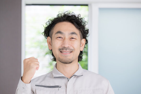 A Japanese remodeling contractor striking a victory pose with a smile&mdash;a reliable male staff member who handles home repairs, construction, estimates, and home fixtures