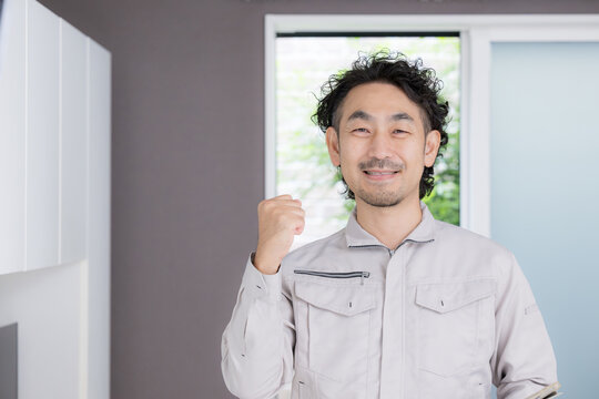 笑顔でガッツポーズをする日本人のリフォーム業者、住宅修理、施工、見積もり、住宅設備に対応する頼れる男性スタッフ