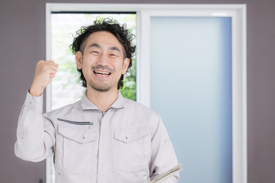 笑顔でガッツポーズをする日本人のリフォーム業者、住宅修理、施工、見積もり、住宅設備に対応する頼れる男性スタッフ
