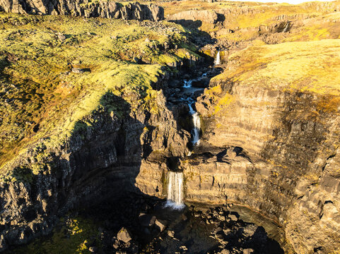 Aerial view of the scenery over a mountain range with waterfall - Iceland