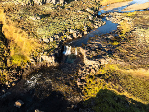 Aerial view of the scenery over a mountain range with waterfall - Iceland