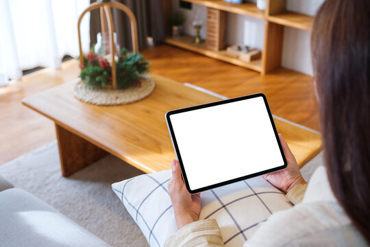 Mockup image of a woman holding tablet with blank desktop white screen at home