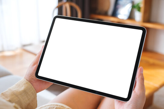 Mockup image of a woman holding tablet with blank desktop white screen at home