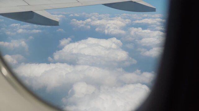 Passenger airplane window view of clouds and blue sky