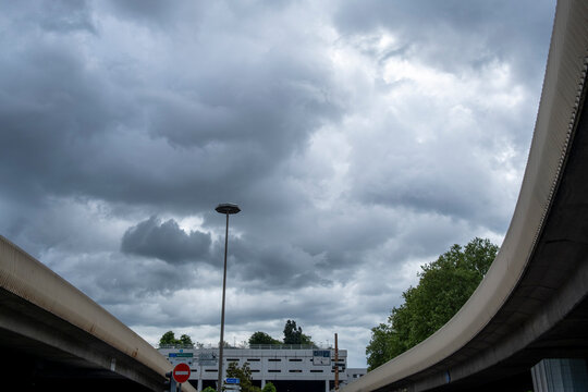 Curving road overpasses frame dramatic storm clouds in Lyon France creating an urban infrastructure view with traffic routes and open sky