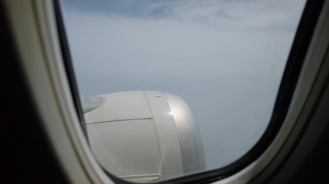 Passenger airplane window view of clouds and blue sky