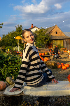 Young woman posing at rustic autumn pumpkin farm during golden hour. Young woman posing among pumpkins in a rustic autumn setting during golden hour.