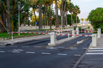 Automatic boom barrier gates at an entrance to a parking area with palm trees © dimas830
