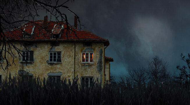 Creepy abandoned haunted house with glowing window under stormy night sky