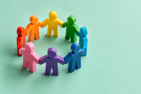 Colorful wooden figures standing in a circle holding hands symbolizing corporate teamwork and global community unity