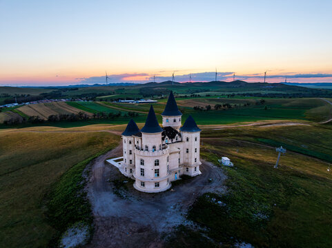 Isolated Castle with Wind Turbines at Sunset